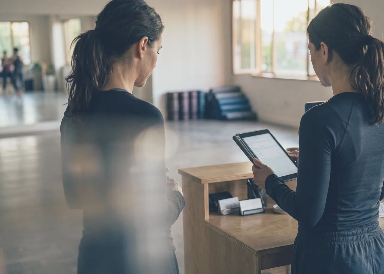 Zwei Instruktorinnen gehen am Studiotresen die Lektionen des Tages auf einem Tablet durch